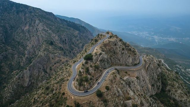 Winding mountain road hugging rocky ridge hairpin switchbacks and valley views