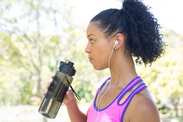 Close-up of female jogger drinking water in the park
