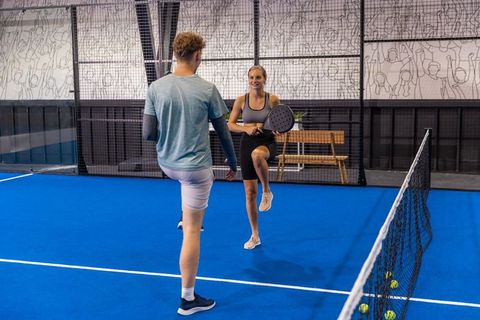 Padel players warming up on vibrant blue indoor court training footwork and racket control