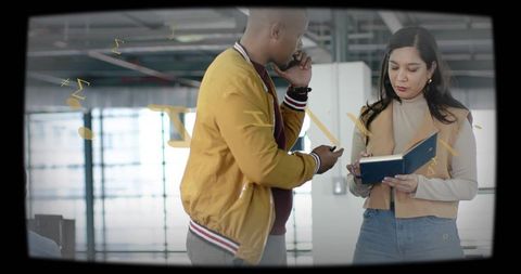 Colleagues checking smartphone and planner in modern sunlit open-plan office