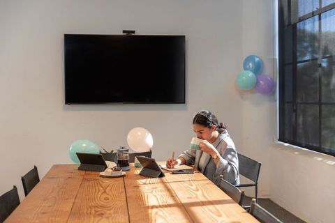 Businesswoman Enjoying Coffee and Working at Conference Table with Balloons