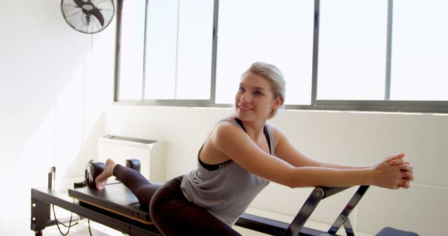 Young Woman Practicing Reformer Pilates in Well-lit Studio - Download Free Stock Images Pikwizard.com