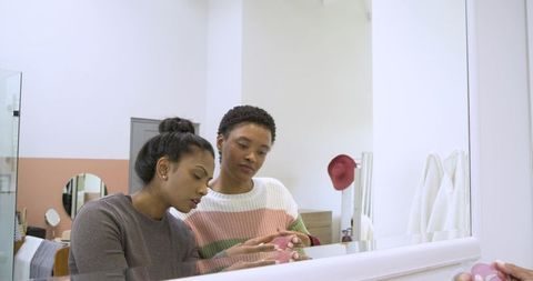 Diverse friends discussing skincare routine in modern bathroom