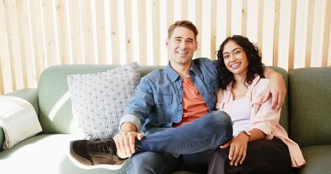 Diverse Couple Relaxing on Modern Sofa Brightly Smiling