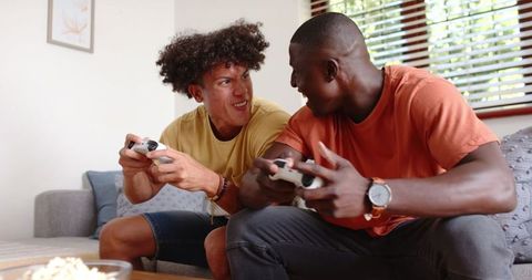 Diverse male friends excitedly playing video games at home