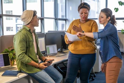 Diverse team collaborating over document in modern open-plan office workspace