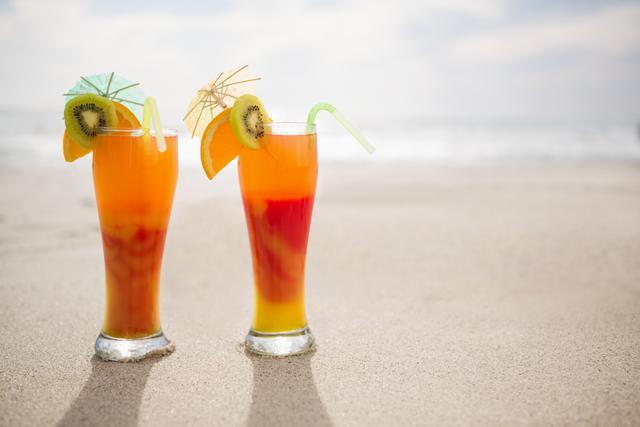 Two glasses of cocktail drink kept on sand at tropical beach