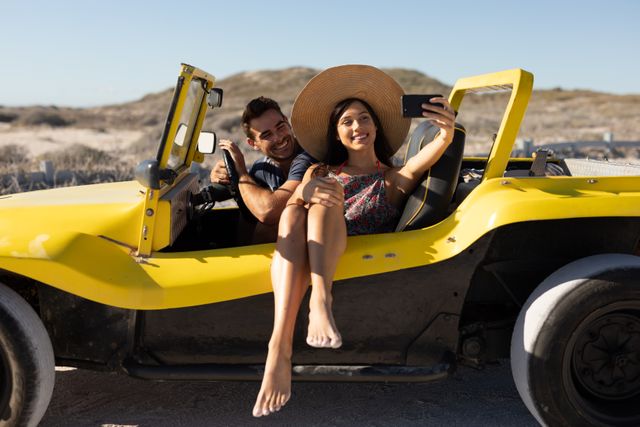 Couple enjoying a sunny day at the beach, sitting in a yellow beach buggy and taking a selfie. Ideal for use in travel blogs, vacation advertisements, romantic getaway promotions, and lifestyle magazines. Perfect for illustrating themes of adventure, leisure, and summer fun.