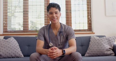 Smiling Male Nurse Relaxing on Couch in Medical Uniform
