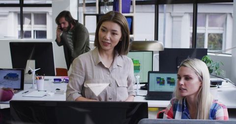 Women Collaborating on Sustainable Energy Design at Computer Workstation with Wind Turbine Model