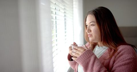 Relaxed woman enjoying tea by a sunlit window