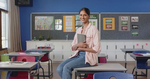 Smiling Teacher Holding Tablet in Modern Classroom Setting