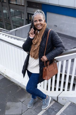Senior african american commuter talking on phone on urban overpass with handbag and scarf