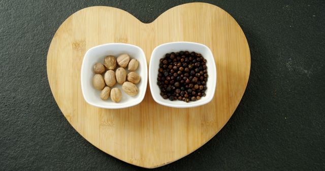 Two types of spices are neatly placed in a heart-shaped wooden bowl on a dark surface, with copy space. The presentation suggests a theme of cooking with love or healthy eating.