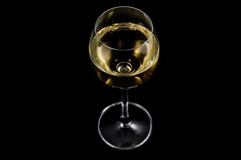 Golden white wine in elegant stem glass overhead on black background for luxury branding