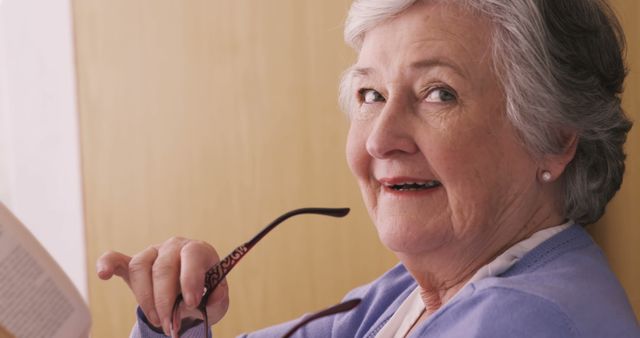 Elderly Woman Smiling While Holding Glasses and Reading Book - Download Free Stock Images Pikwizard.com