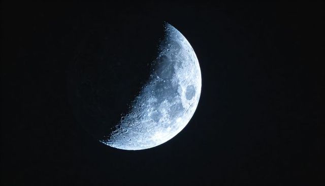 Crescent moon close-up revealing crater details and sharp terminator in night sky