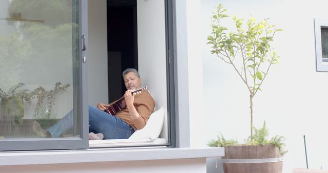 Man Relaxing at Home Playing Guitar Near Window - Download Free Stock Images Pikwizard.com