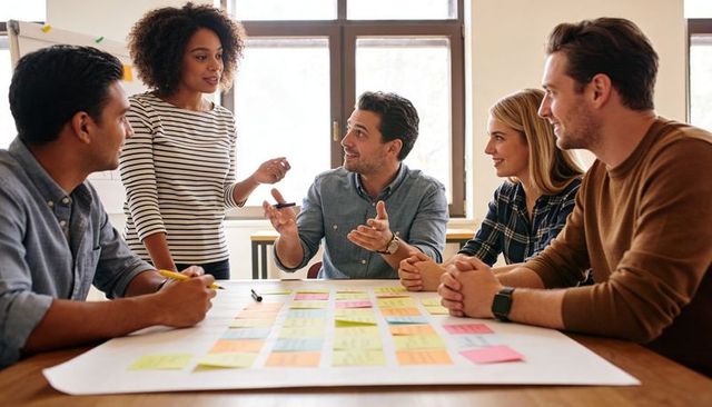 Team brainstorming around colorful sticky notes while leader presenting project plan