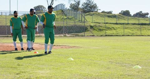 Diverse Baseball Team Practicing Outfield Drills in Green Uniforms with Training Cones