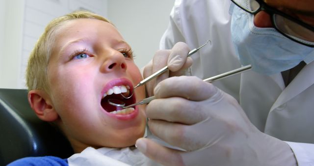 Young boy receiving a dental examination from a dentist in a clinic. Ideal for illustrating children's healthcare, dental services, oral hygiene education, and promoting pediatric dentistry services.