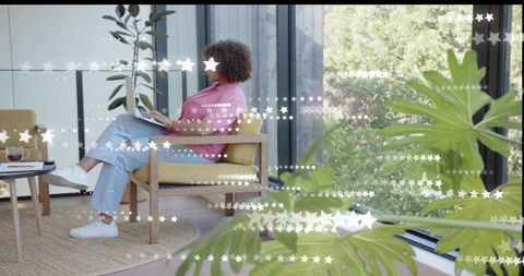 Woman working from home in cozy modern lounge with laptop, plants and star window decals