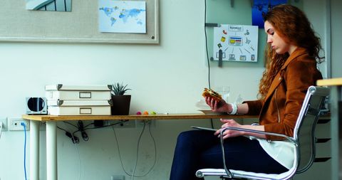 Young Executive Balancing Meal Time and Work in Modern Office