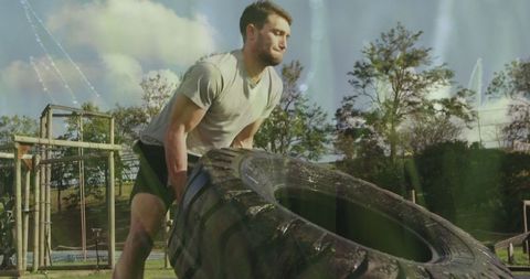 Athlete flipping tire in outdoor strength training course