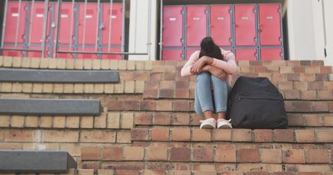 Adolescent seeking solace outside school lockers
