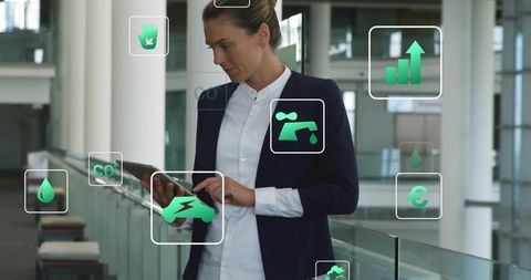 Executive tapping tablet with floating green sustainable and fintech icons in glass atrium