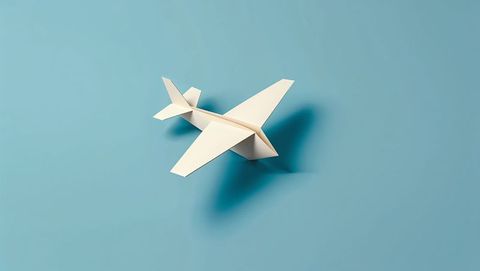 Minimalist white paper airplane on light blue background
