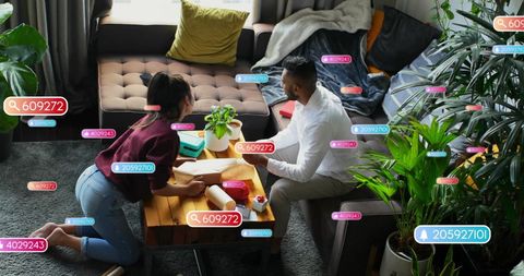 Diverse couple wrapping presents with social media notifications