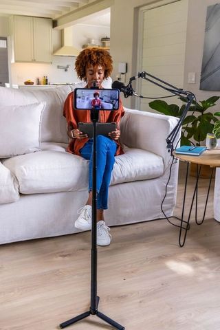 African american creator recording home podcast with tablet, phone tripod and microphone