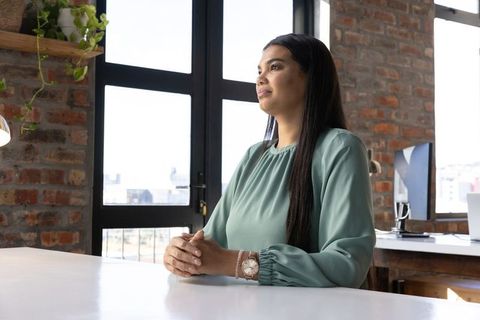 Professional woman in loft office looking thoughtful