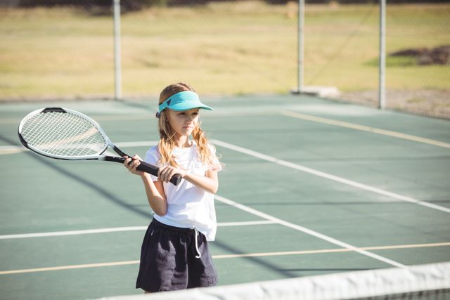 Girl playing tennis at court on sunny day