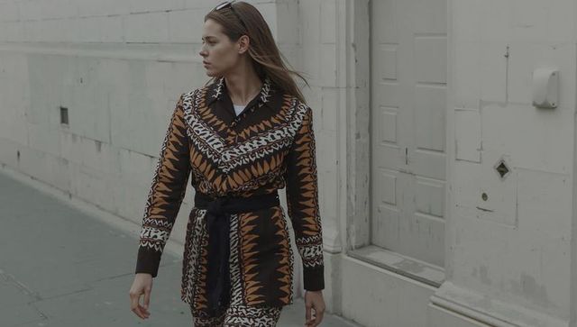 Walking Woman Wearing Patterned Sash Outfit on Urban Street Looking Left