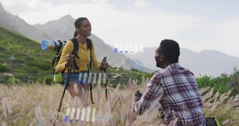 Hiking partners pausing in mountain meadow hydrating and enjoying scenic view