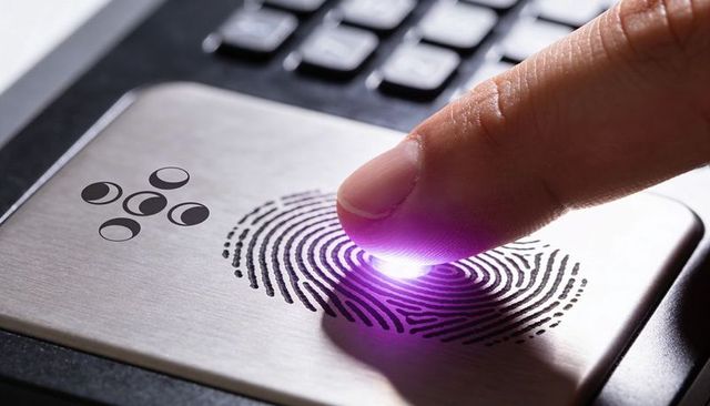 Fingerprint authentication scanning on laptop sensor with purple led glow