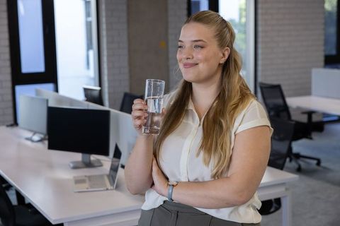 Professional Woman Hydrating in Modern Open Office Work Environment