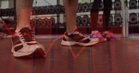 Partners training in gym sneakers on rubber floor with red performance graph overlay