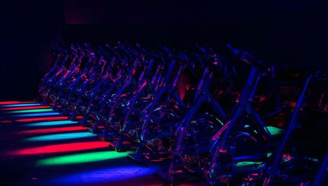 Neon-lit row of stationary bikes in modern cycling studio