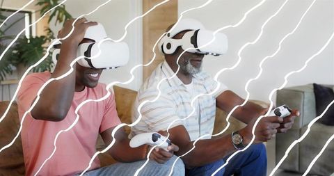 Father and Son Playing Virtual Reality Games on Sofa Wearing VR Headsets with Controllers