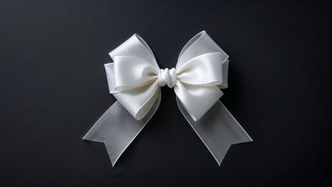 White satin ribbon bow on dark grey background highlighting elegance