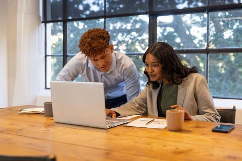 Diverse colleagues collaborating over laptop and charts in modern office boosting teamwork