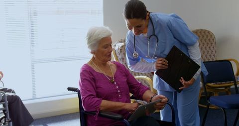 Caucasian Doctor Assisting Senior Woman with Tablet in Nursing Home