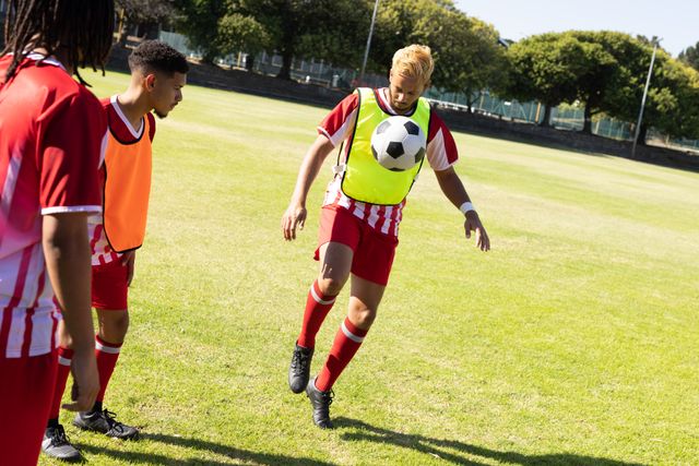Multiracial soccer players practicing freestyle skills on a sunny field. Ideal for content related to sports training, teamwork, athleticism, and outdoor activities. Perfect for promoting soccer events, fitness programs, and team-building exercises.