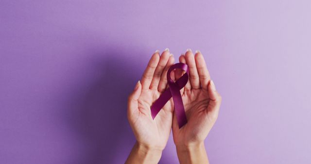 Image of hands of caucasian woman holding purple ribbon on violet background. medicine, health, cancer awareness concept digitally generated image.