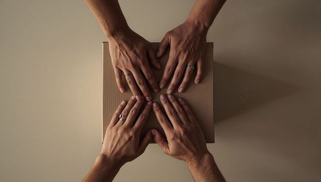 Couple resting hands on cardboard parcel conveying intimacy, trust, partnership, minimal