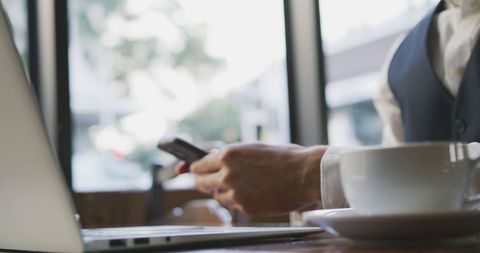 Businessman managing work mobile and laptop cafe