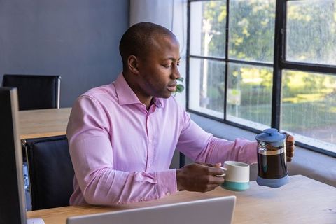 Man in Office Pouring Coffee from French Press into Cup